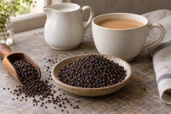 Kräftiger gebrochener Schwarztee neben Frühstückstasse und Milchkännchen
