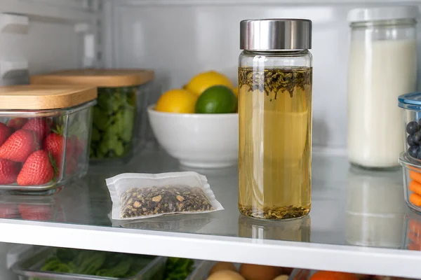 Eine verschlossene Aufgussflasche und eine kleine unbeschriftete Teepackung im Kühlschrank
