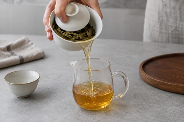 Ein Gaiwan wird über einer Servierkanne vollständig ausgegossen