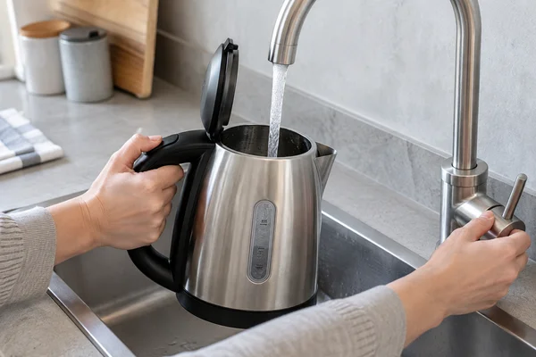 Frisches Wasser wird an der Spüle in einen Wasserkocher gefüllt