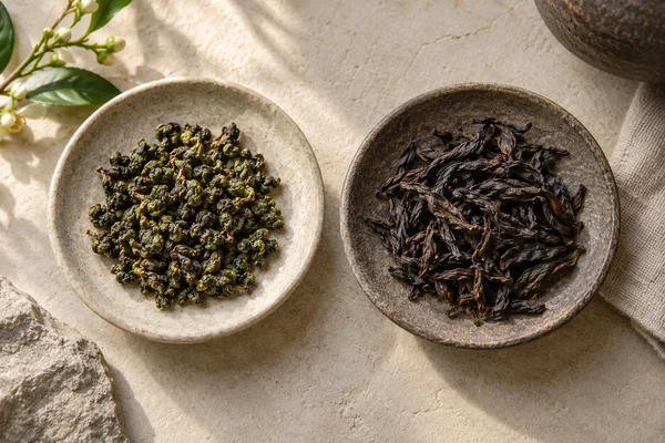 Grün gerollter Oolong neben dunklen gedrehten Blättern eines gerösteten Oolongs