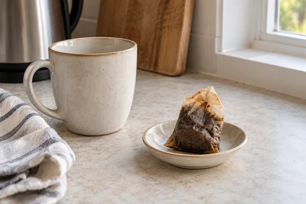 Ein benutzter Teebeutel liegt auf einer kleinen Untertasse