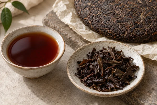 Dunkle Shou-Pu-Erh-Blätter, ein Teefladen und rotbrauner Tee