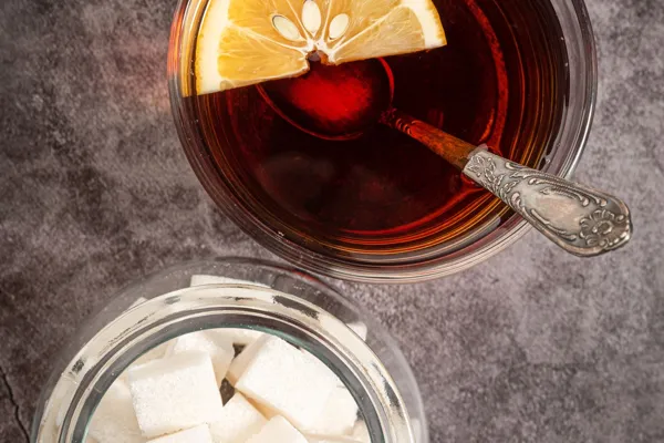 Tee mit Zitrone neben einem Glas mit Zuckerwürfeln