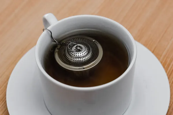 Kleines Tee-Ei aus Metall in einer weißen Tasse